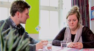 Thuuisbegeleider en cliënt rond de tafel